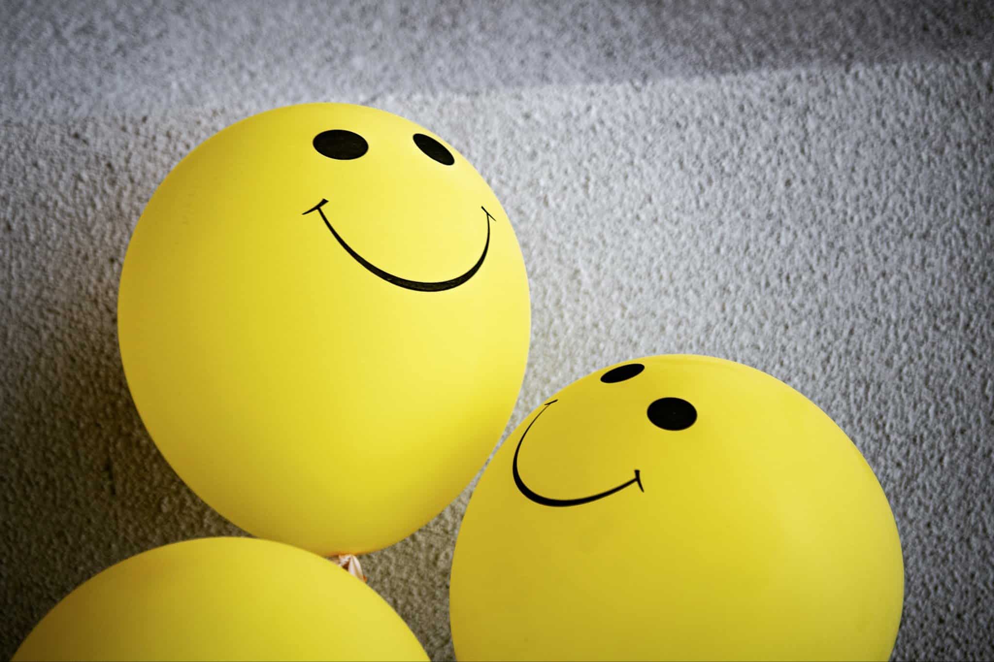 Yellow balloons with happy faces; mental health awareness.