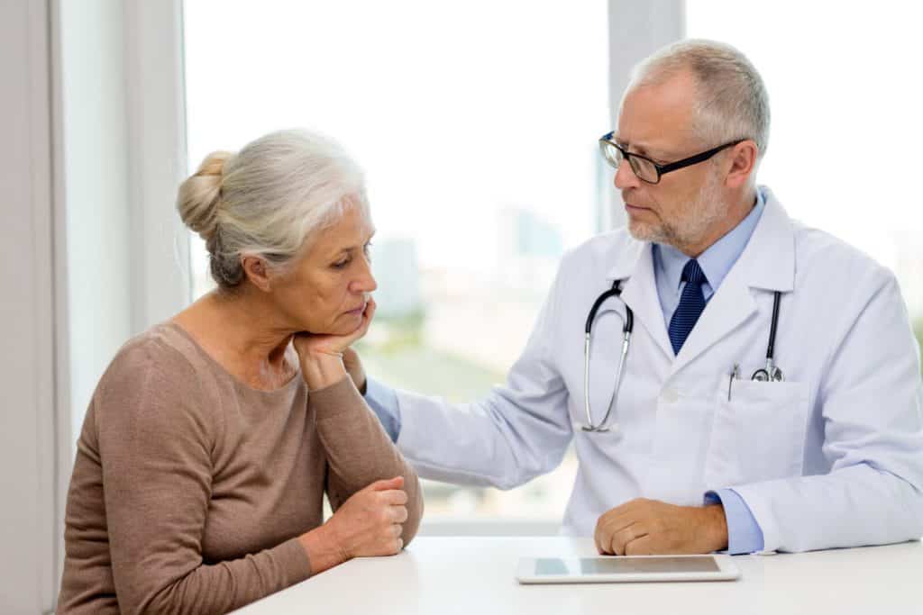Male doctor consoling mature woman